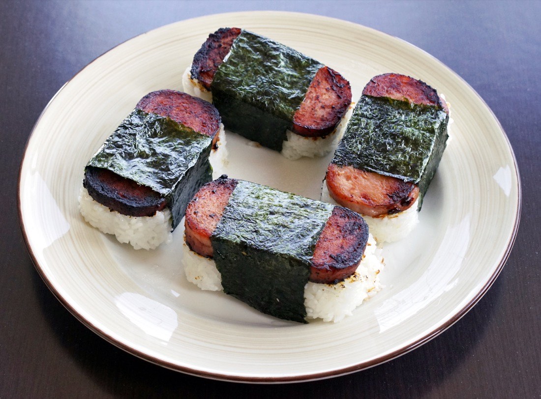 A piece of spam musubi, a slice of Spam pressed onto a block of rice and wrapped in a band of nori